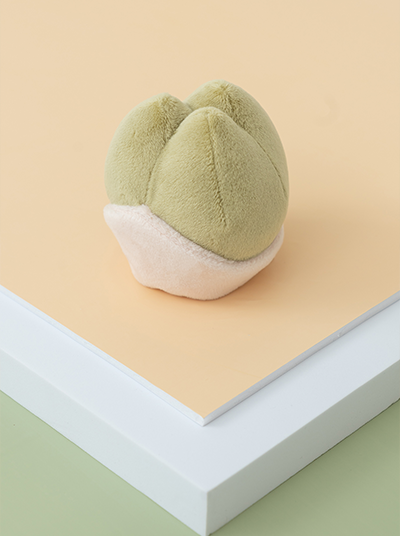Green plush toy resembling a cloud on a beige surface with a white base.
