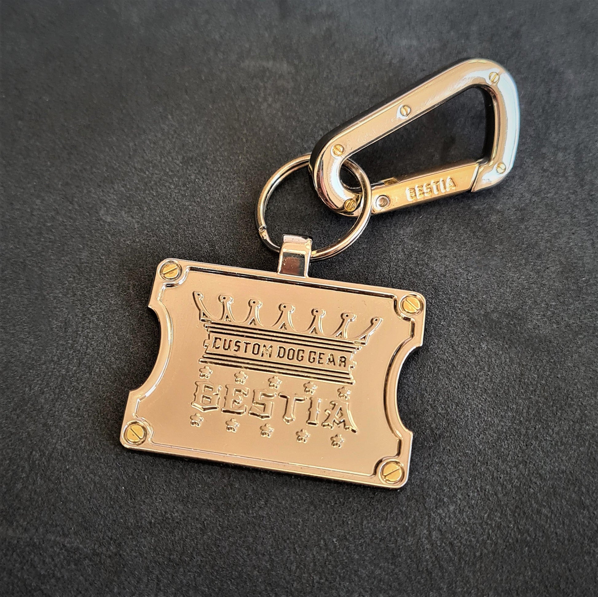 Gold keychain with 'Bessika' branding on a dark background