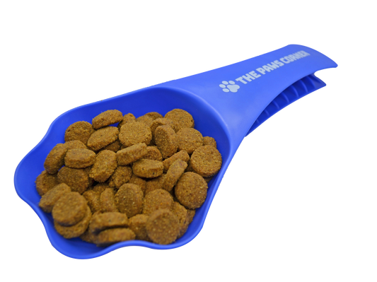 Blue pet food scoop filled with kibble on a white background